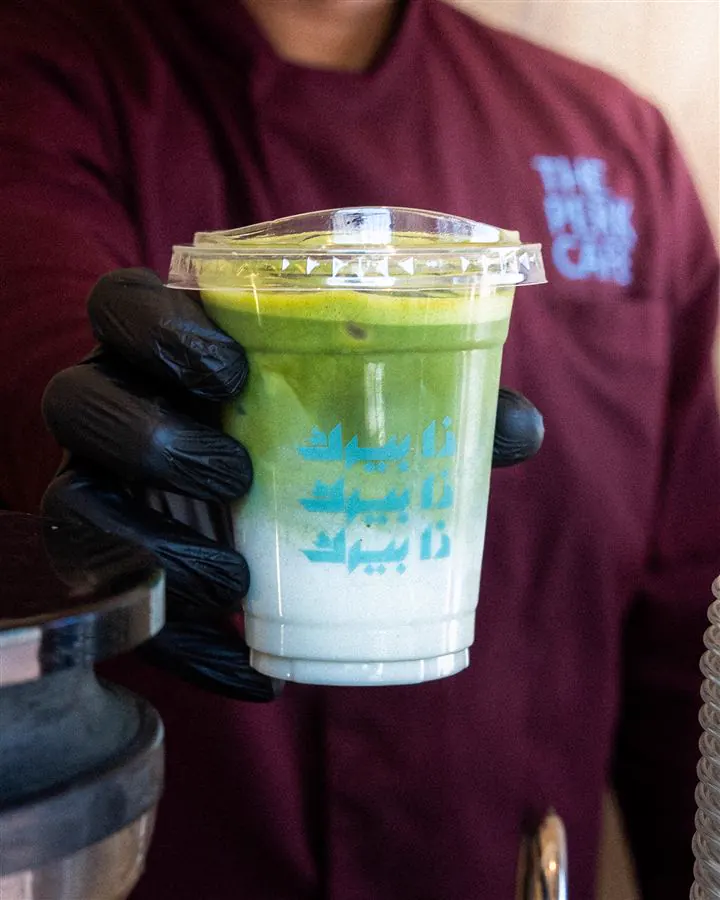 The Perk Cafe: a matcha drink held up by the barista